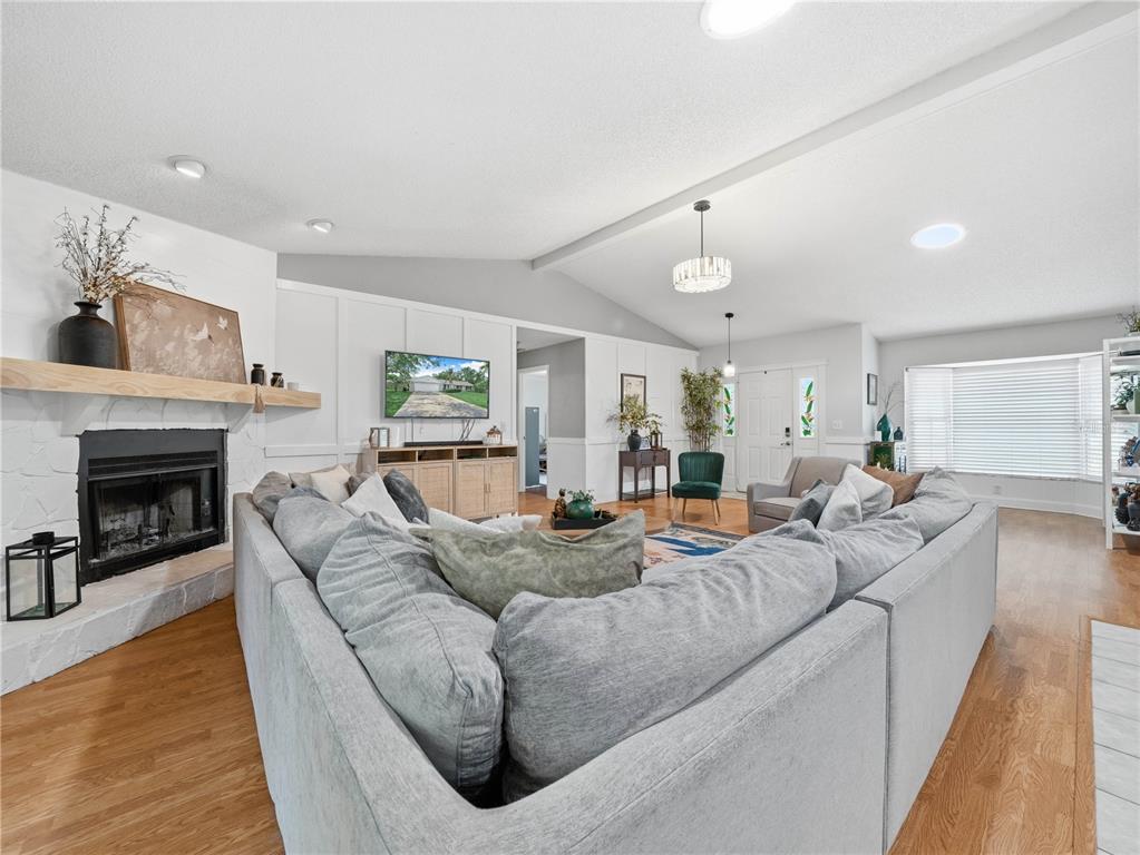 A living room features a stone fireplace, a large sectional sofa, and light wood flooring — 955 TIMBERGREEN DRIVE, LAKELAND, FL