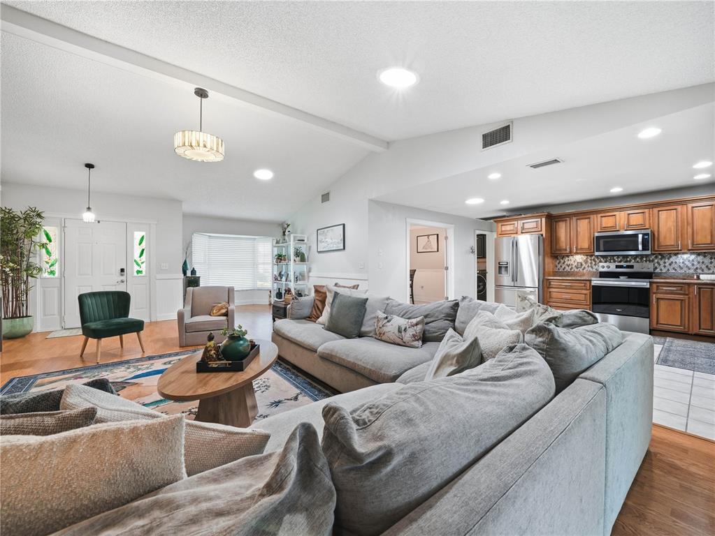 An open-concept living room features a large gray sectional sofa and an adjacent kitchen — 955 TIMBERGREEN DRIVE, LAKELAND, FL