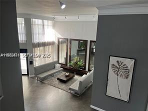 A high-angle view of a modern living room with tall windows, gray sofas, and mirrors — 200 Leslie Dr # 303, Hallandale Beach FL 33009, HALLANDALE BEACH, FL