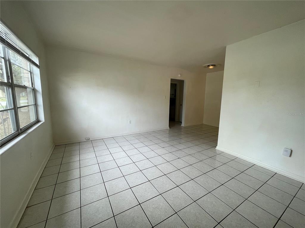 An empty room with white walls, a window, and light-colored square floor tiles — 1600 INDIANA AVENUE, WINTER PARK, FL