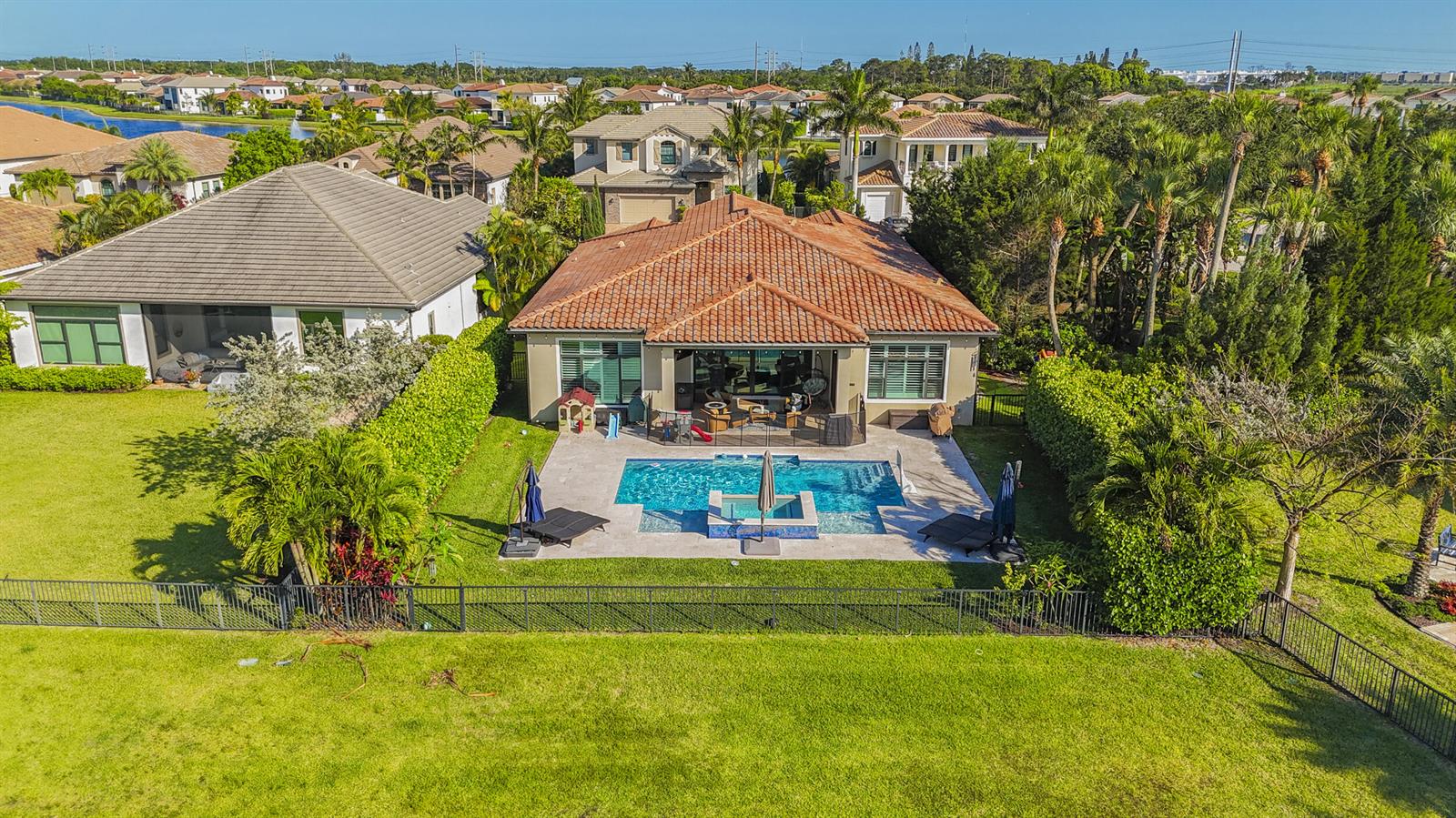 An aerial view of a house with a tiled roof, swimming pool, and fenced backyard — 9387 Grand Prix Lane, Boynton Beach FL 33472, BOYNTON BEACH, FL