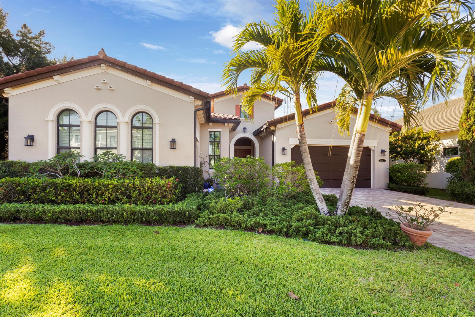 A single-story house with a beige stucco exterior, arched windows, and a palm tree — 9387 Grand Prix Lane, Boynton Beach FL 33472, BOYNTON BEACH, FL