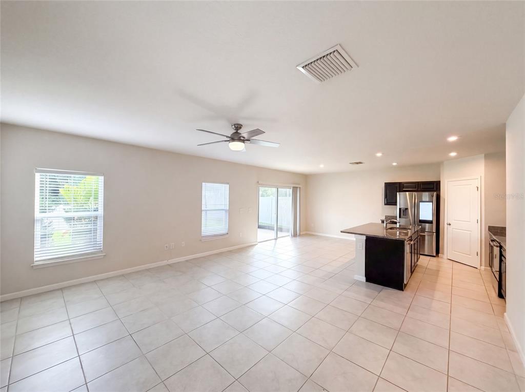An open-concept living area features light tile flooring, a ceiling fan, and a kitchen island — 10654 HAWKS LANDING DRIVE, LAND O LAKES, FL