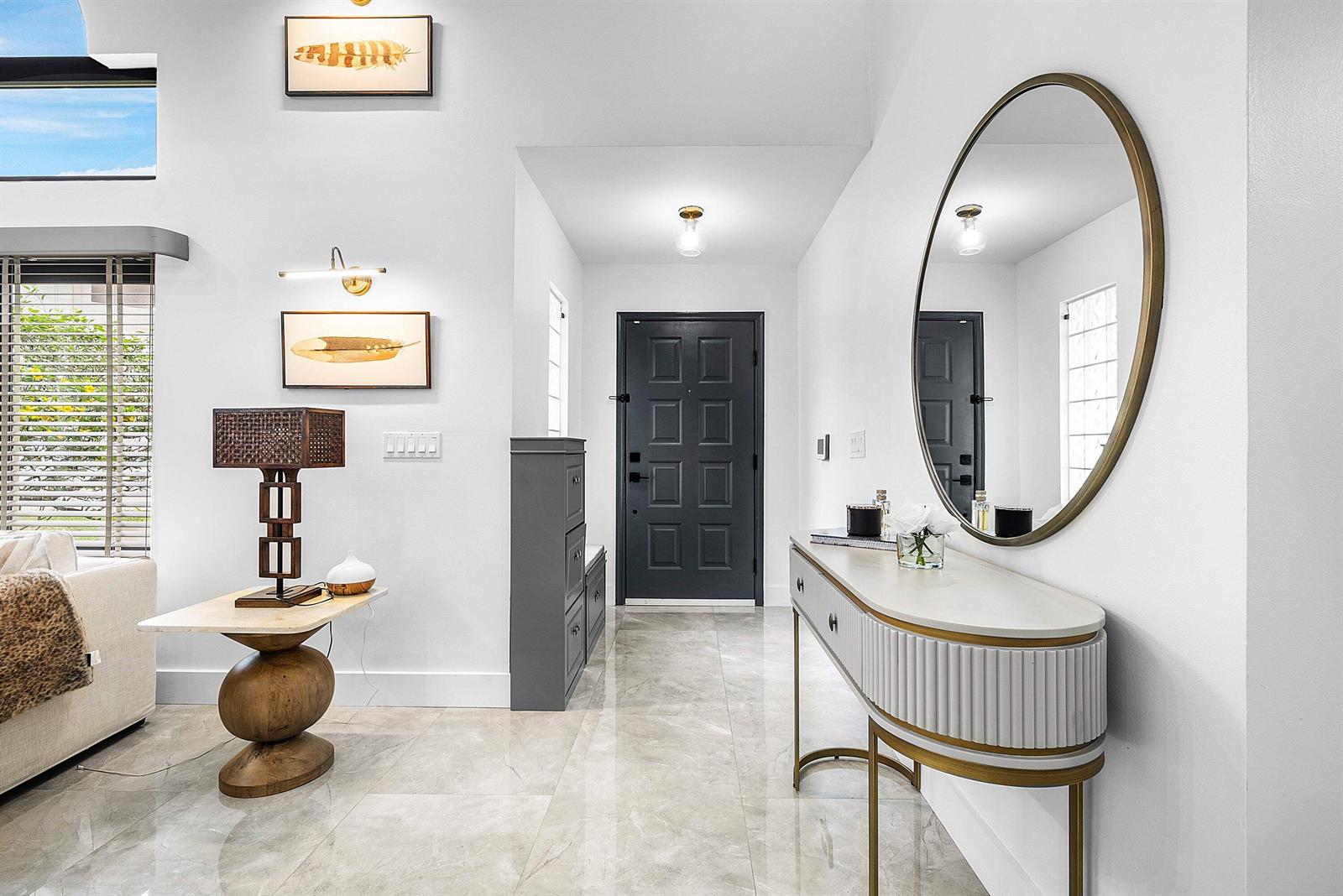 A bright entryway features a dark front door, marble-look tile flooring, and a console table — 20797 Cabrillo Way, Boca Raton FL 33428, BOCA RATON, FL
