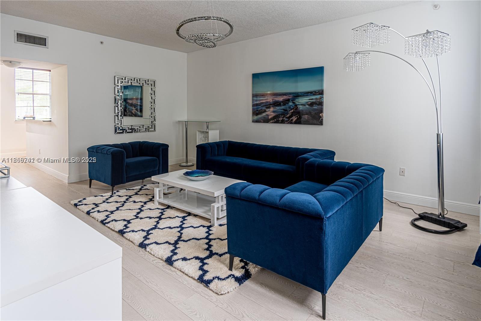 A living room features blue velvet furniture, a patterned rug, and a crystal floor lamp — 2069 S Ocean Dr, Hallandale Beach FL 33009, HALLANDALE BEACH, FL