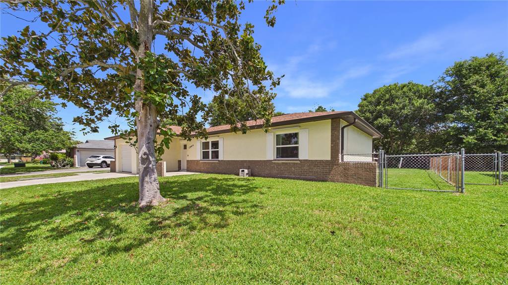 A single-story house with a brick and stucco exterior, a front lawn, and a tree — 1964 W SHORES ROAD, MELBOURNE, FL