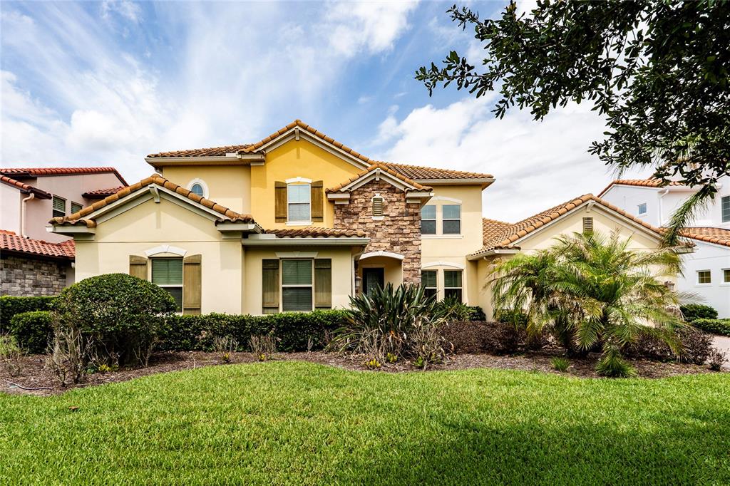 A two-story suburban house with a yellow stucco exterior, stone accents, and a tiled roof — 8530 BAYVIEW CROSSING DRIVE, WINTER GARDEN, FL