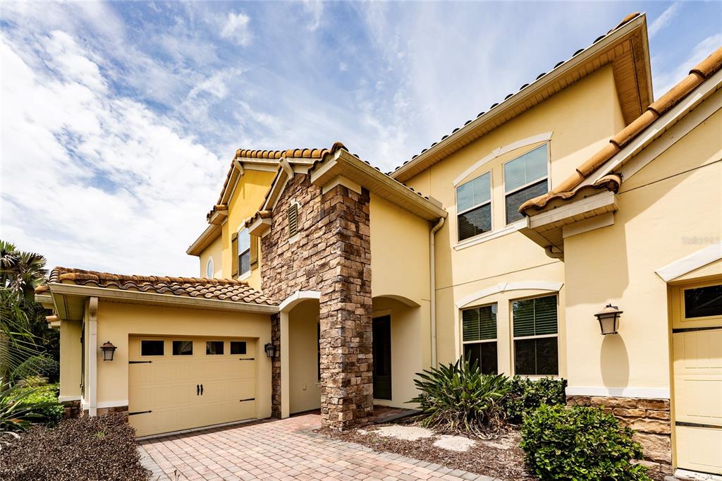 A two-story house with a stone-accented facade, a tile roof, and a paved driveway — 8530 BAYVIEW CROSSING DRIVE, WINTER GARDEN, FL