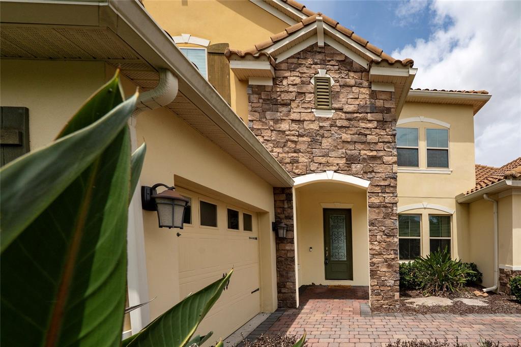 A two-story house exterior features a stone-accented entryway, a garage, and a paved driveway — 8530 BAYVIEW CROSSING DRIVE, WINTER GARDEN, FL