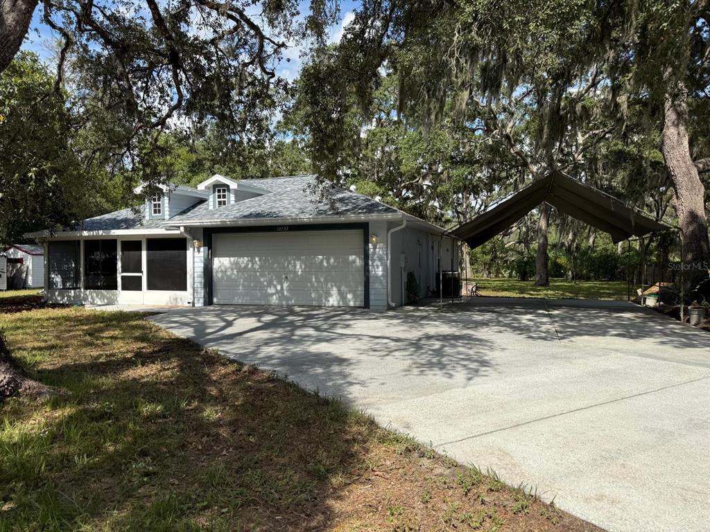 A single-story house with a two-car garage, a screened porch, and a detached metal carport — 10733 OAK DRIVE, HUDSON, FL
