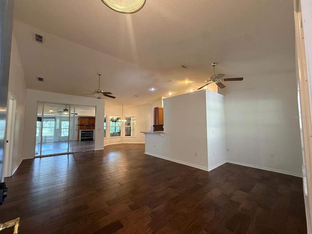 An open-concept living area features dark wood-look tile flooring, vaulted ceilings, and a kitchen island — 10733 OAK DRIVE, HUDSON, FL