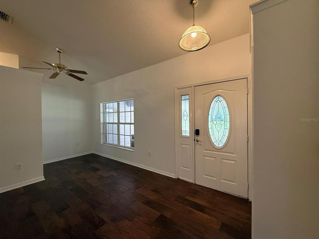 An entryway with dark wood flooring, a white front door, and a ceiling light fixture — 10733 OAK DRIVE, HUDSON, FL