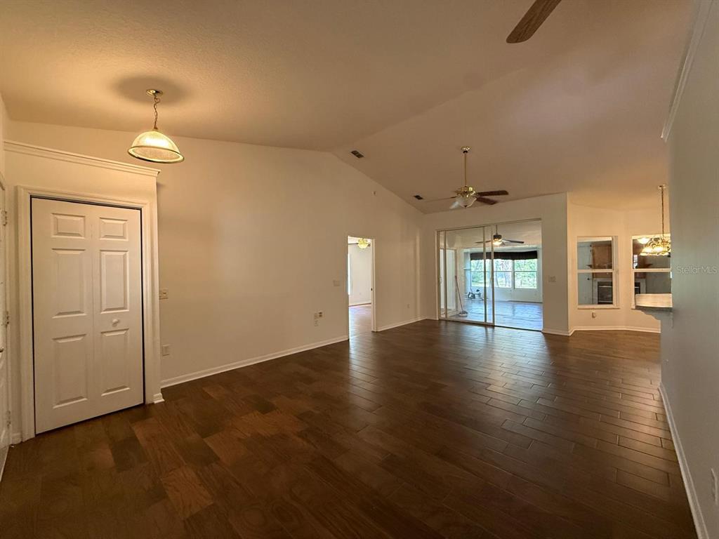 A living room with vaulted ceilings, dark wood flooring, and a sliding glass door — 10733 OAK DRIVE, HUDSON, FL