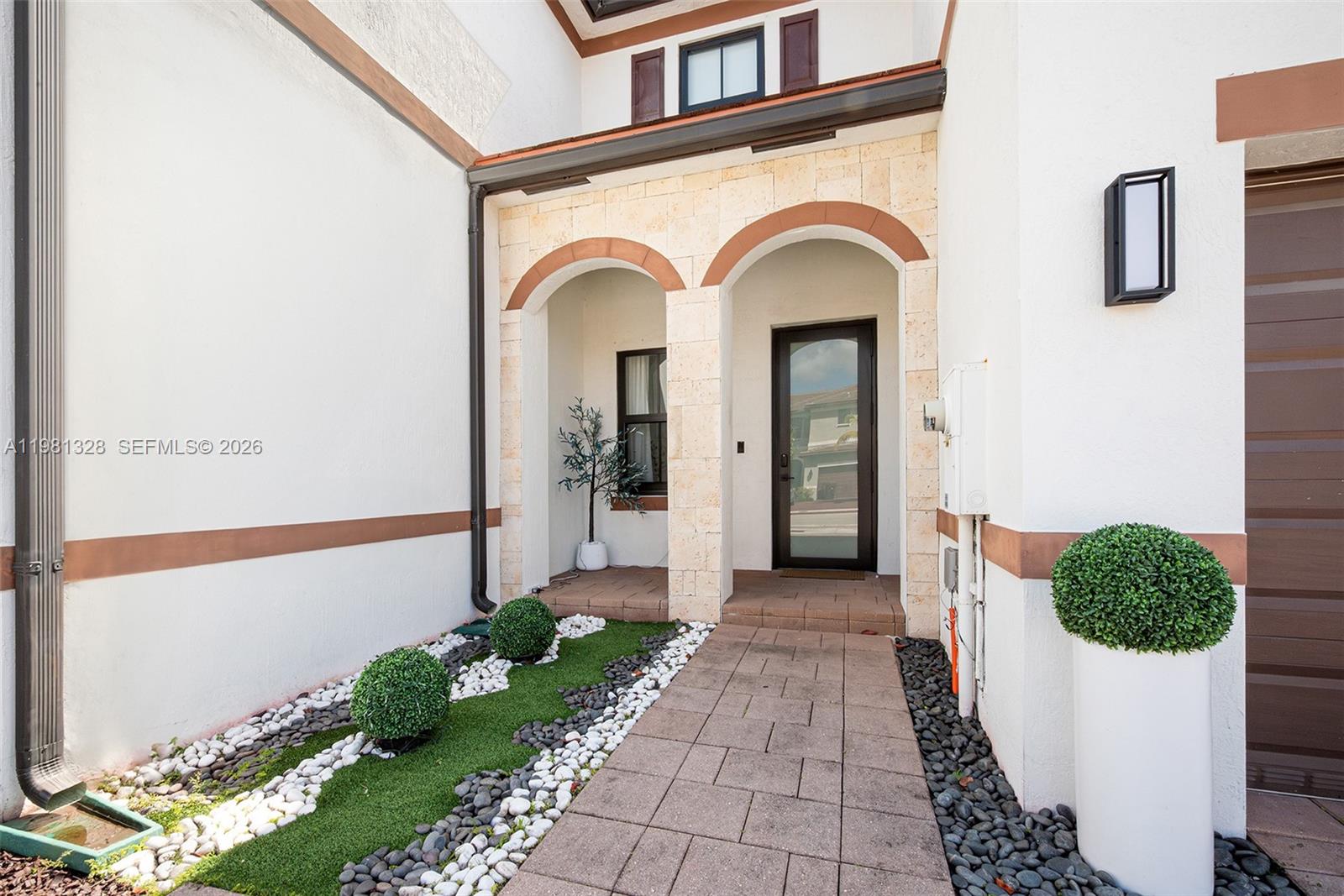 The exterior entrance features a stone-arched doorway, a paved walkway, and decorative landscaping — 3438 W 104th Ter, Hialeah FL 33018, HIALEAH, FL
