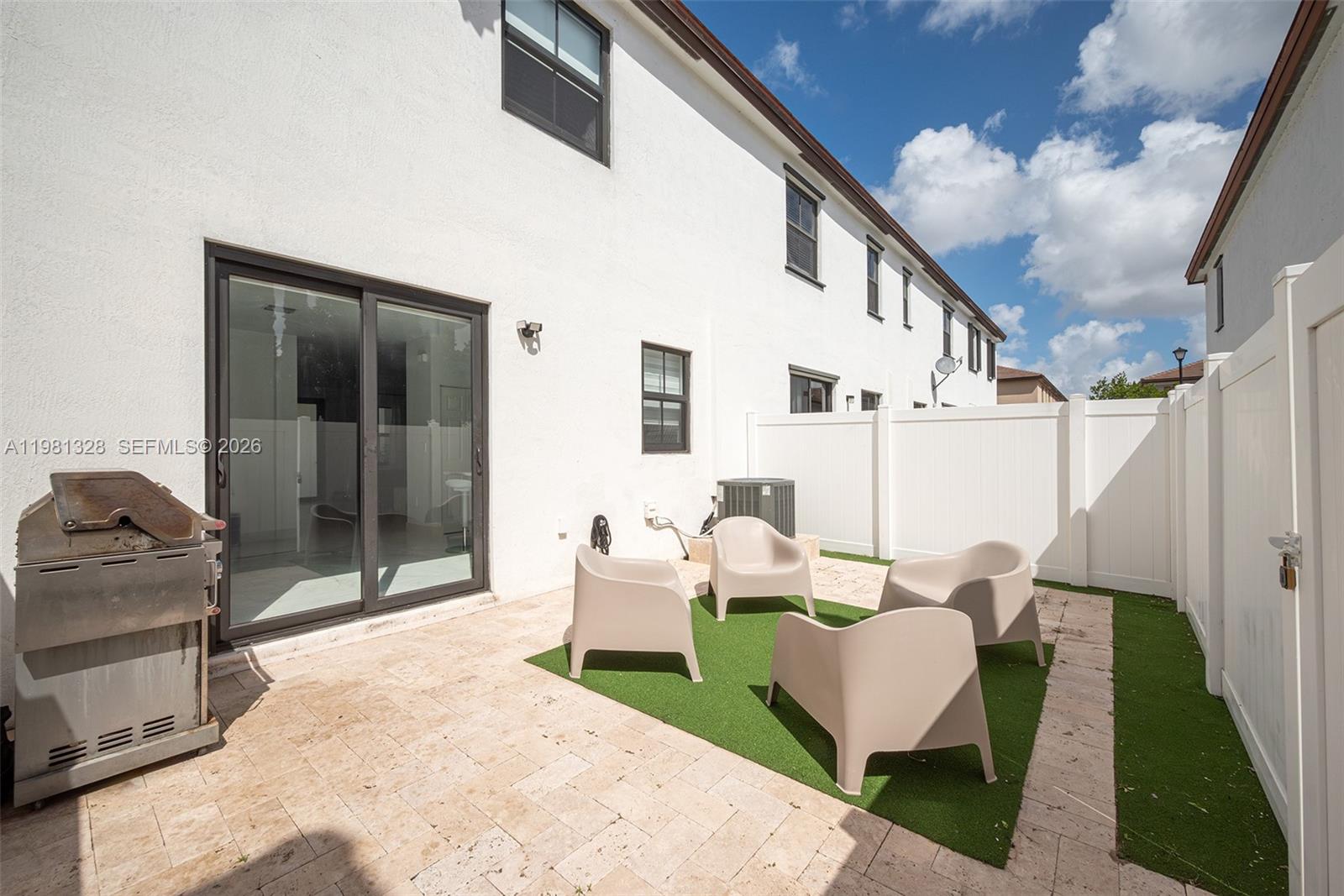 A small patio features a stone floor, artificial turf, four chairs, and a metal grill — 3438 W 104th Ter, Hialeah FL 33018, HIALEAH, FL