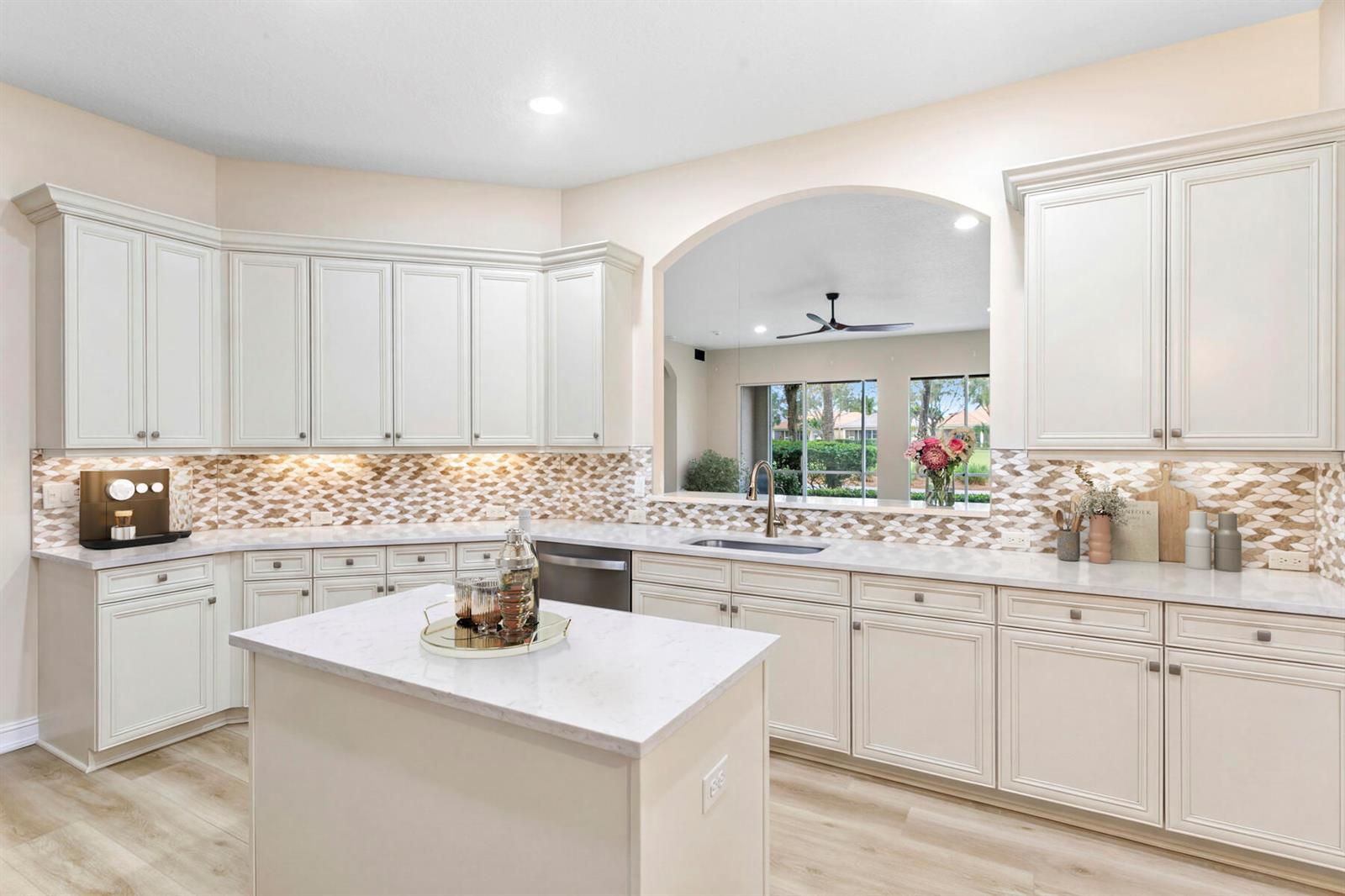 A dining area features wood-look flooring, a chandelier, a window with palm tree views, and cabinets — 10263 Orchid Reserve Drive # 21b, FL 33412, FL