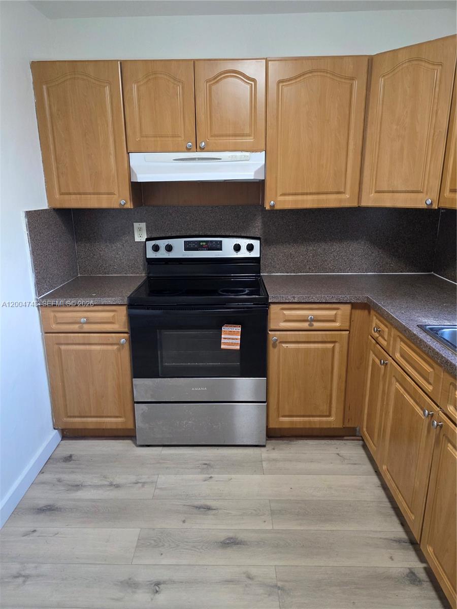 A kitchen features wood cabinets, a black Amana stove, and brown speckled countertops — 1111 NW 19th Ave # 205, Miami FL 33125, MIAMI, FL
