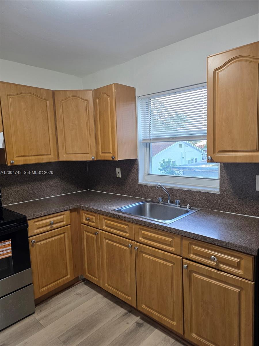 A kitchen features light wood cabinets, a dark speckled countertop, and a stainless steel sink — 1111 NW 19th Ave # 205, Miami FL 33125, MIAMI, FL