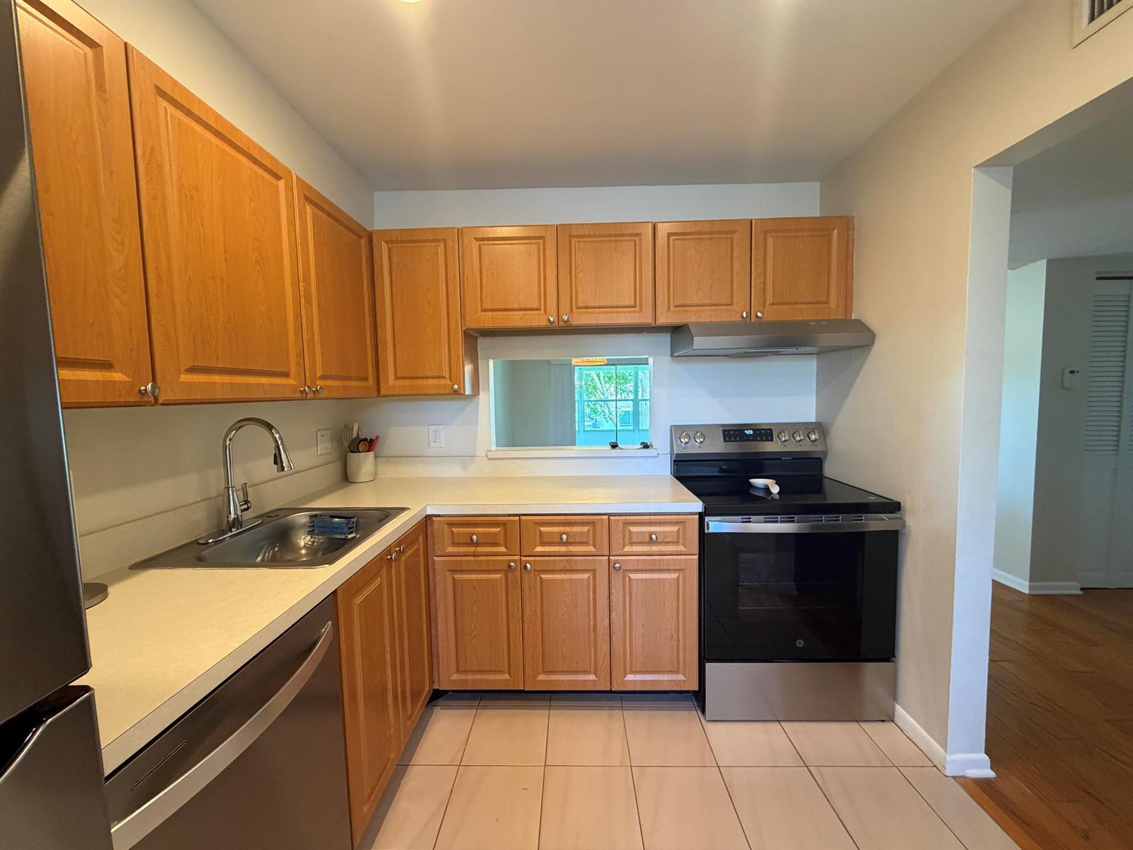 A kitchen features wood cabinets, stainless steel appliances, a sink, and light-colored tile flooring — 2800 Fiore Way # 201, Delray Beach FL 33445, DELRAY BEACH, FL