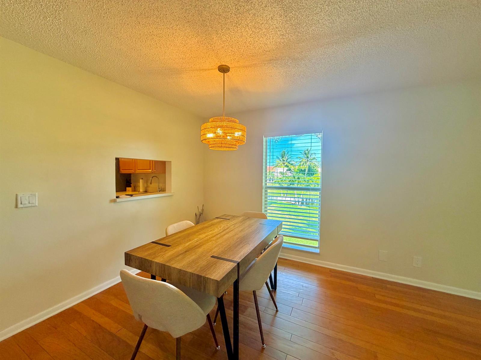 A dining room features a wooden table, four chairs, a woven pendant light, and window views — 2800 Fiore Way # 201, Delray Beach FL 33445, DELRAY BEACH, FL