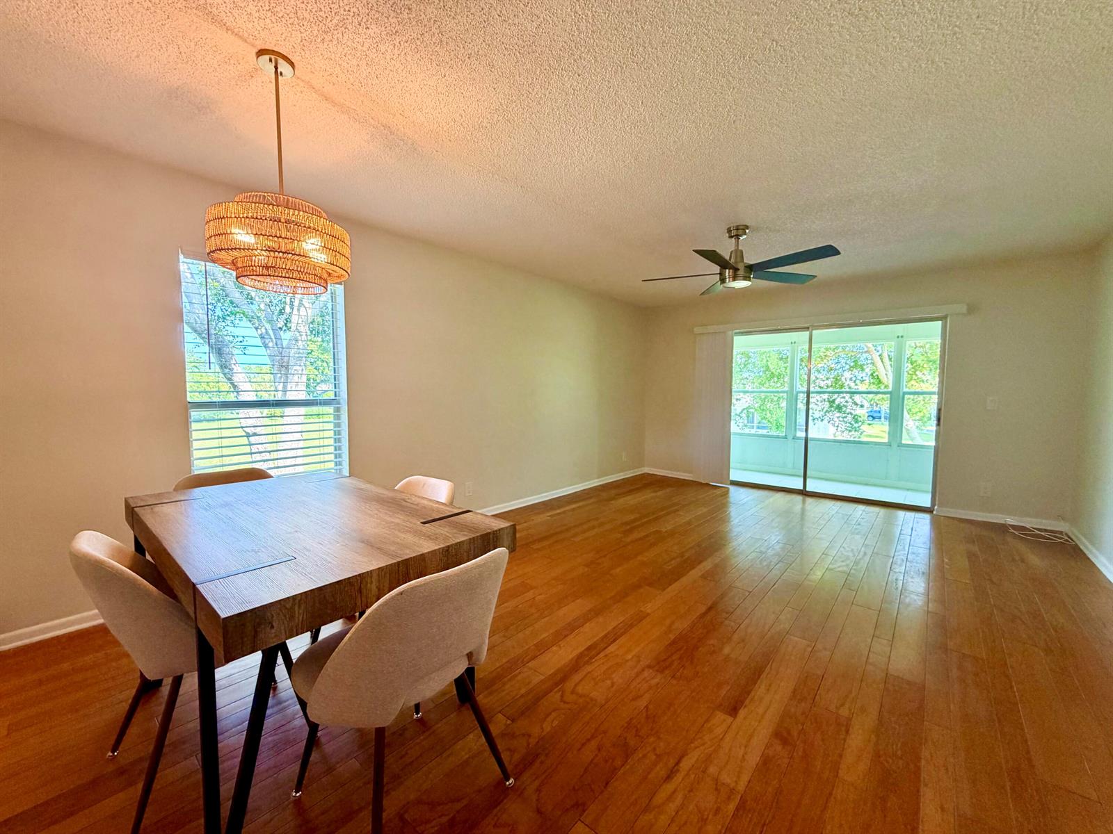 A dining area with a wood table and pendant light opens into a living space — 2800 Fiore Way # 201, Delray Beach FL 33445, DELRAY BEACH, FL