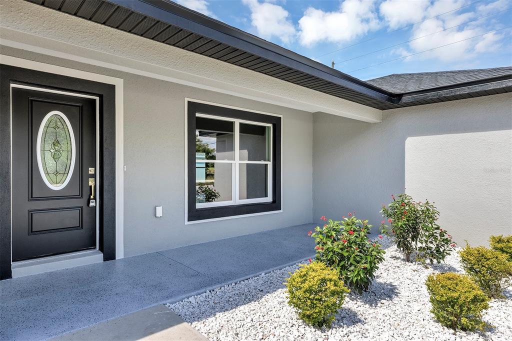The exterior of a house features a gray front door, a window, and landscaping — 10415 SW 140TH AVENUE, DUNNELLON, FL