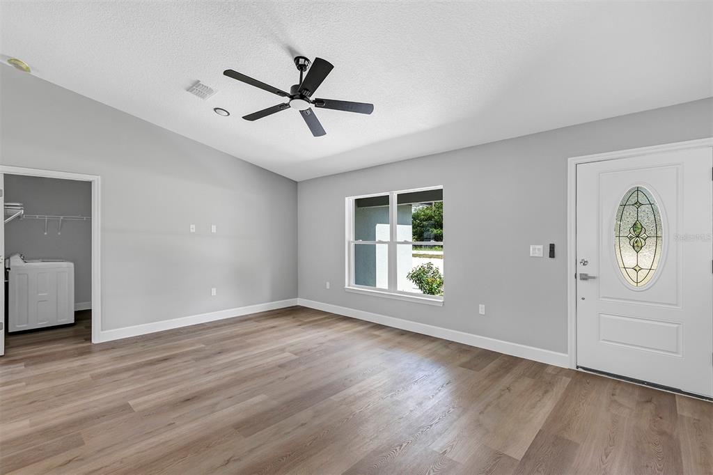 A room with light gray walls, wood-look flooring, a ceiling fan, and a front door — 10415 SW 140TH AVENUE, DUNNELLON, FL