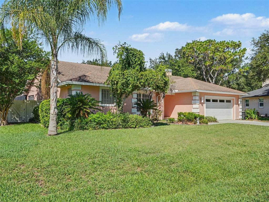 A single-story peach-colored house with a brown shingled roof and a two-car garage — 2124 VELVET WAY, LAKELAND, FL