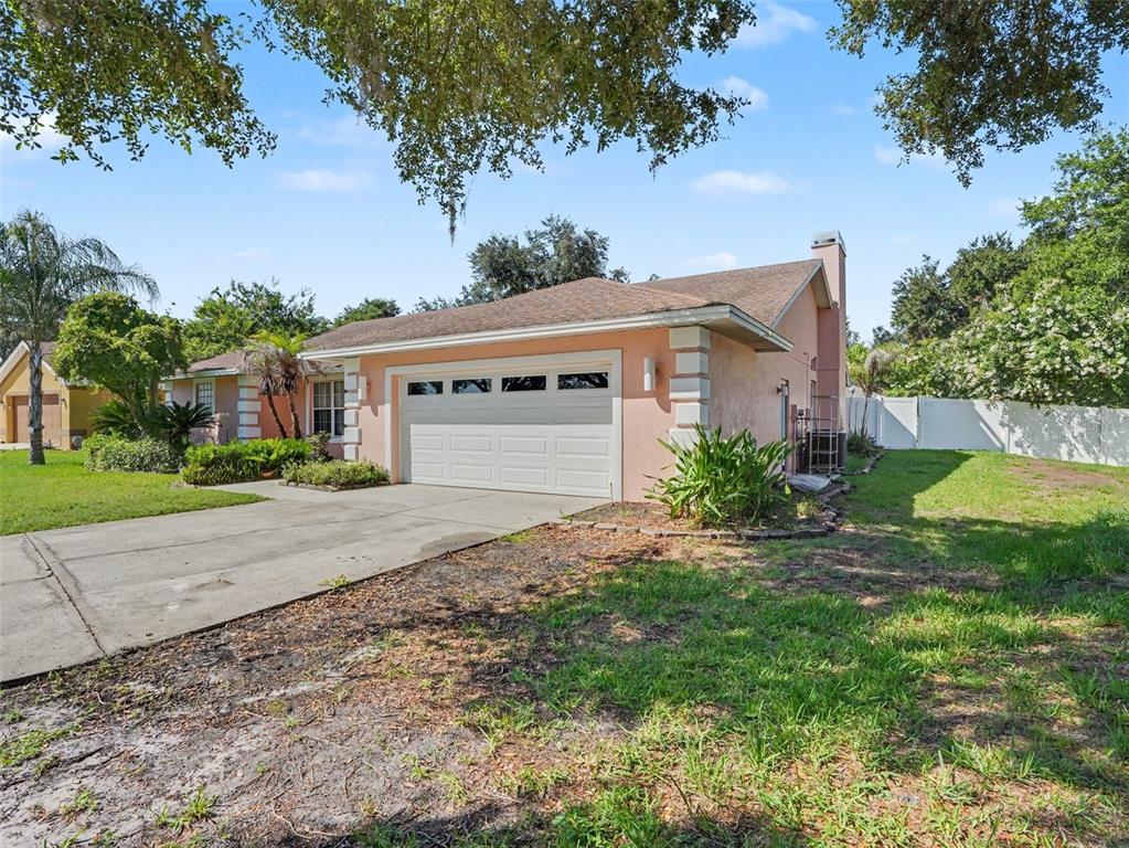 A pink single-story house with a two-car garage and a chimney on the side — 2124 VELVET WAY, LAKELAND, FL
