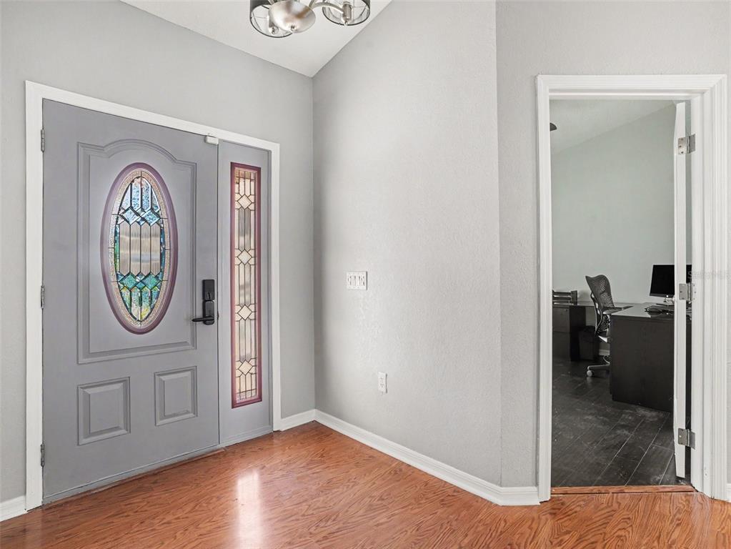 An entryway with a gray front door, hardwood floors, and an adjacent office doorway — 2124 VELVET WAY, LAKELAND, FL