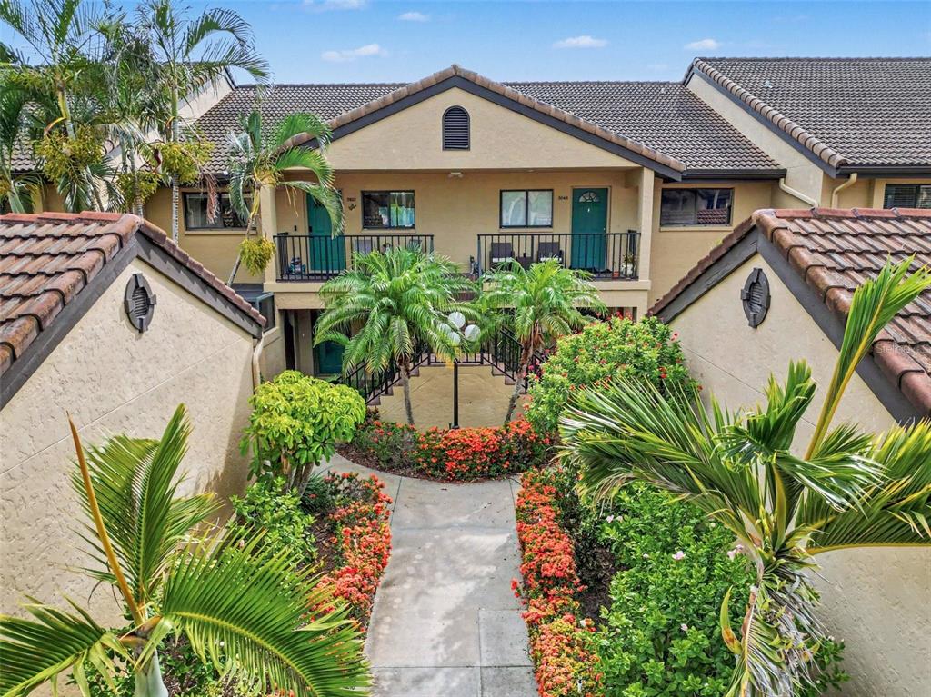 A walkway leads through a landscaped courtyard to the entrance of a two-story apartment building — 5652 ASHTON LAKE DRIVE UNIT 5652, SARASOTA, FL