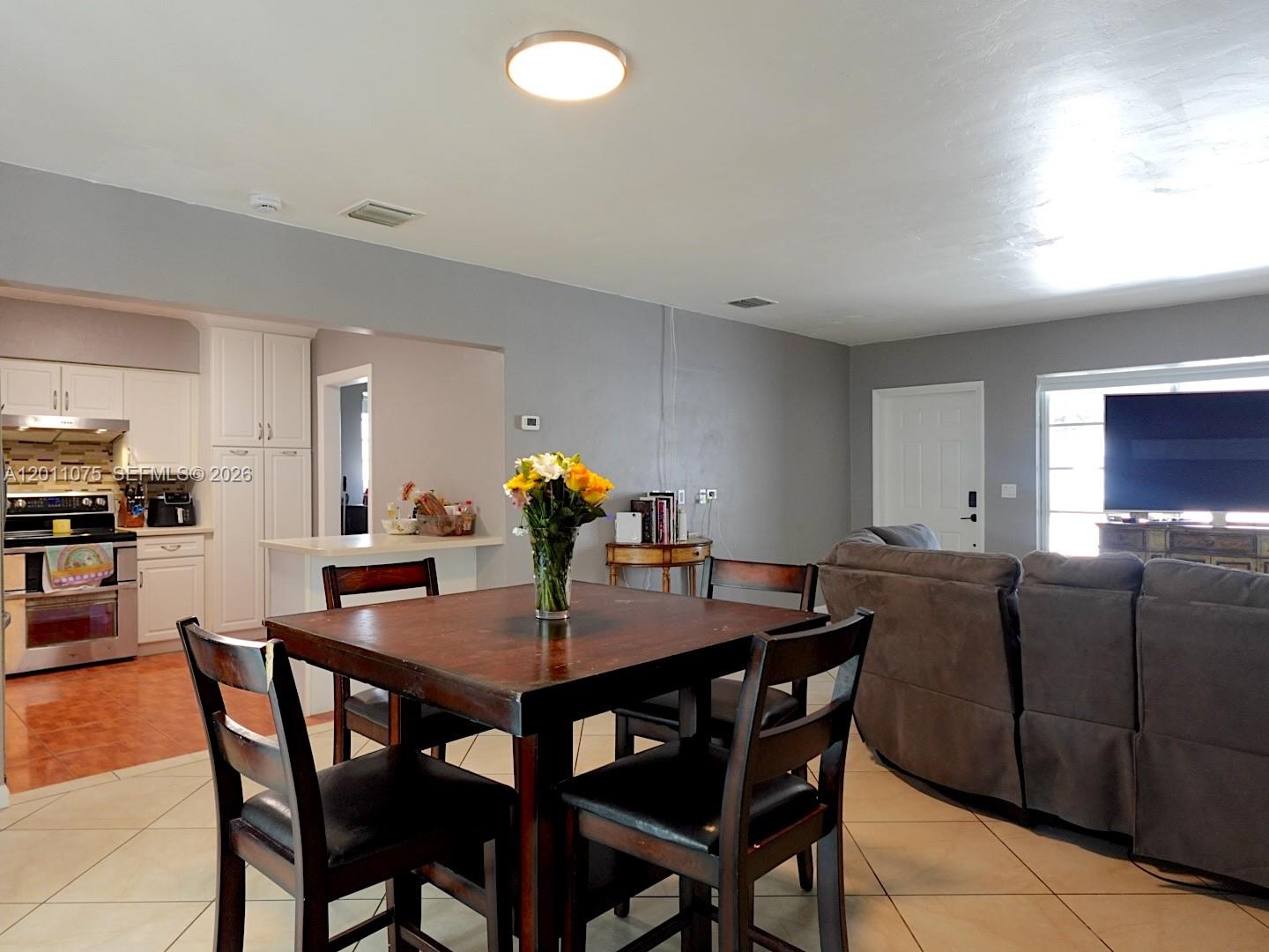 A dining area with a wooden table and chairs is adjacent to an open kitchen — 730 N 73rd Ave, Hollywood FL 33024, HOLLYWOOD, FL