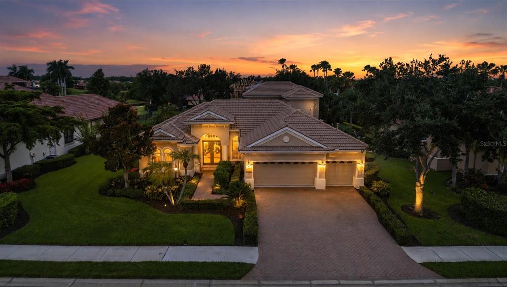 A living room with a curved sofa, tile floors, and an arched opening to a dining area — 6806 DOMINION LANE, LAKEWOOD RANCH, FL