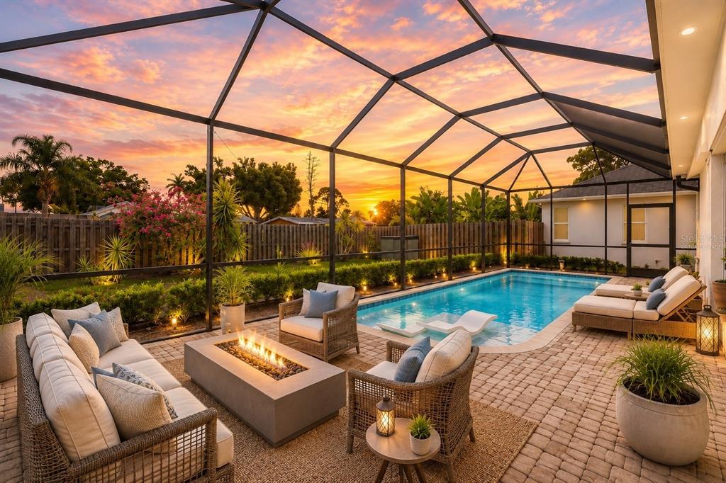 A screened-in patio features a swimming pool, a fire pit, and outdoor lounge furniture at sunset — 5425 MATTHEW COURT, SARASOTA, FL
