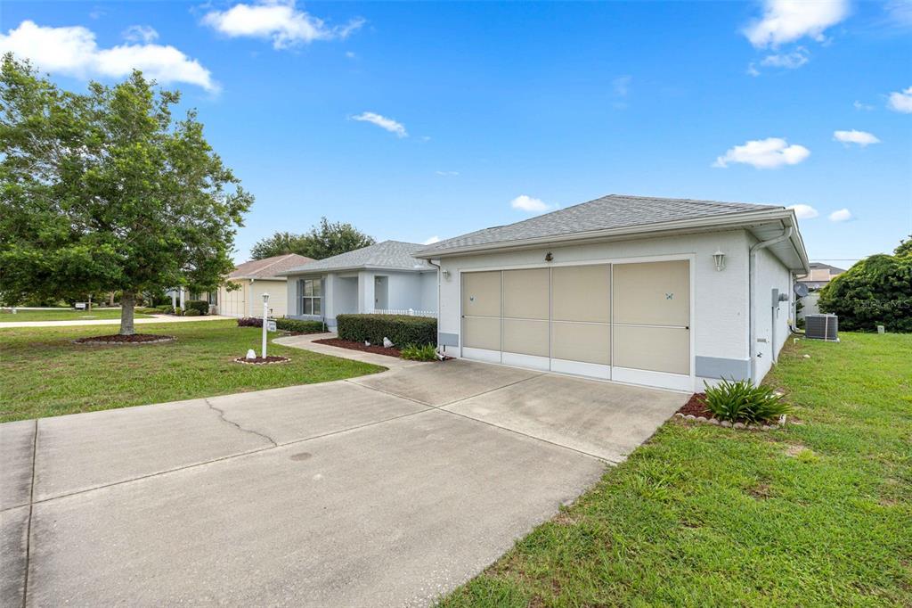 A single-story house with a concrete driveway and a garage featuring a screen door — 8459 SW 60TH COURT, OCALA, FL