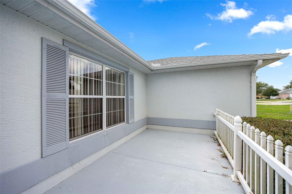 A concrete patio features a white railing, gray shutters, and a large window — 8459 SW 60TH COURT, OCALA, FL