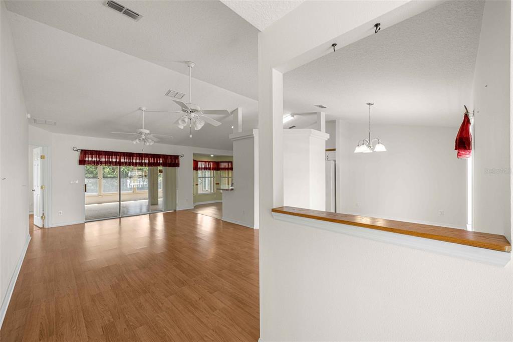 A view from a hallway looking into a living room with wood-look flooring and ceiling fans — 8459 SW 60TH COURT, OCALA, FL