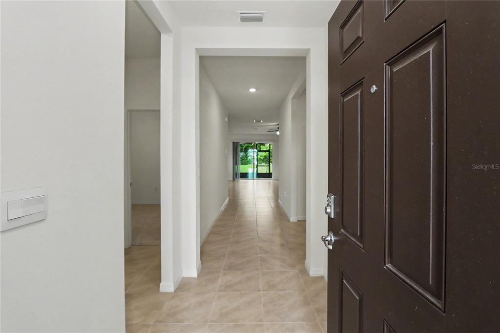 A view from an open front door looking down a tiled hallway toward a patio — 6265 SW 88 LOOP, OCALA, FL