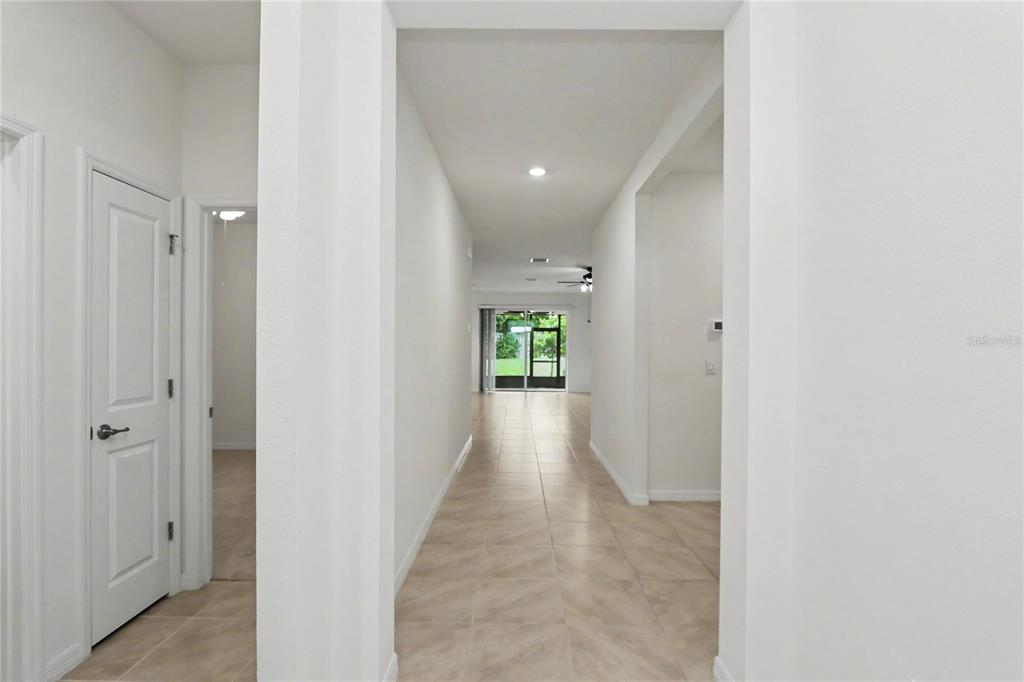 A tiled hallway leads from an entryway toward a glass sliding door overlooking a backyard — 6265 SW 88 LOOP, OCALA, FL