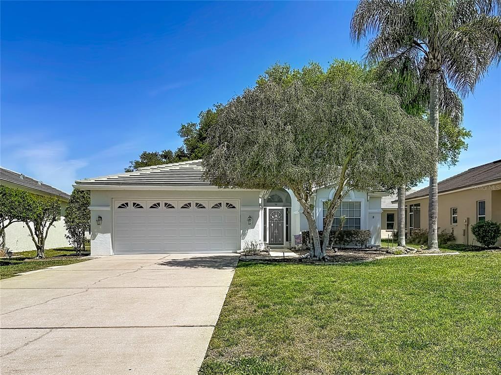 A single-story house with a white exterior, a two-car garage, and a large front tree — 9289 PENELOPE DRIVE, WEEKI WACHEE, FL