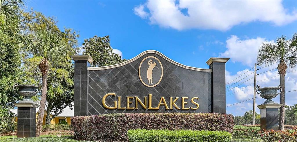 A stone monument sign for GlenLakes stands outdoors surrounded by palm trees and landscaping — 9289 PENELOPE DRIVE, WEEKI WACHEE, FL