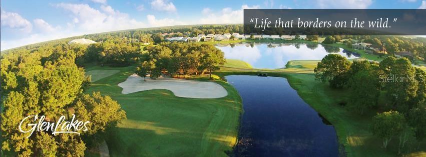 An aerial view shows a golf course fairway with a sand bunker and a large pond — 9289 PENELOPE DRIVE, WEEKI WACHEE, FL