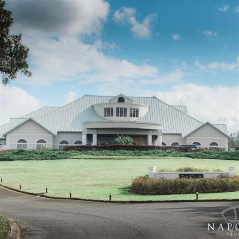 A large, light-colored building with a metal roof sits behind a circular driveway and lawn — 9289 PENELOPE DRIVE, WEEKI WACHEE, FL