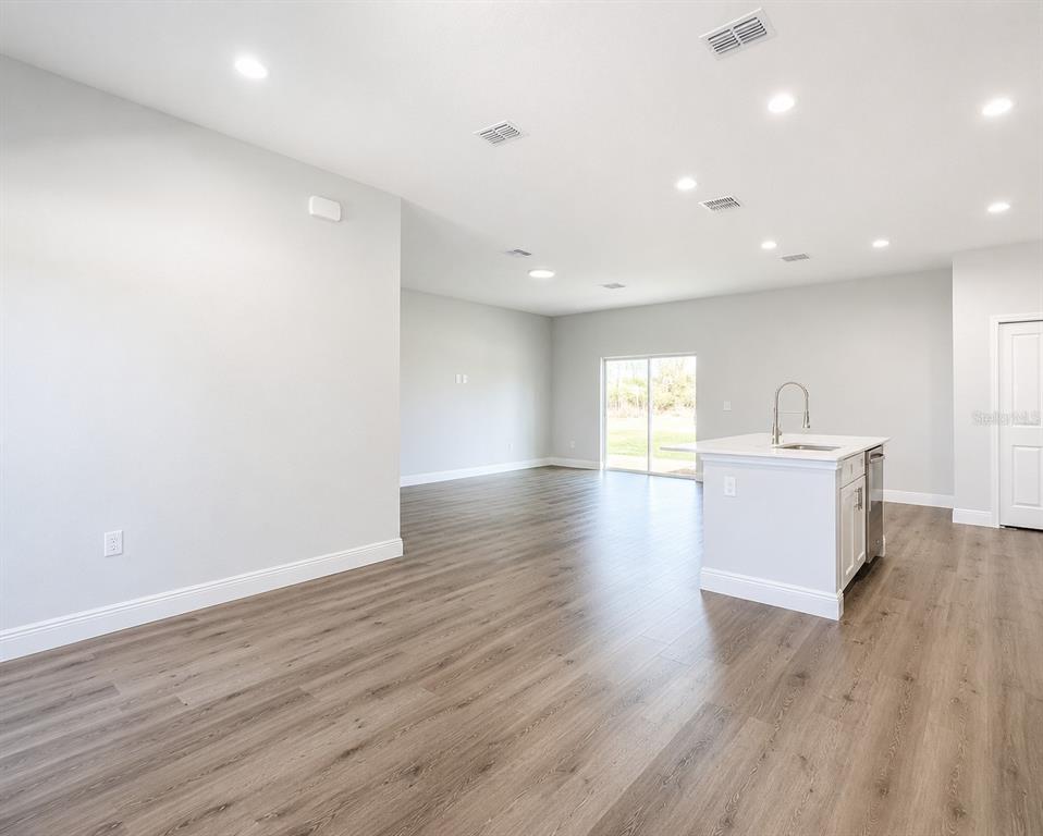 An open-concept living area features light gray walls, wood-look flooring, and a kitchen island — 39 WATER TRACK DRIVE, OCALA, FL