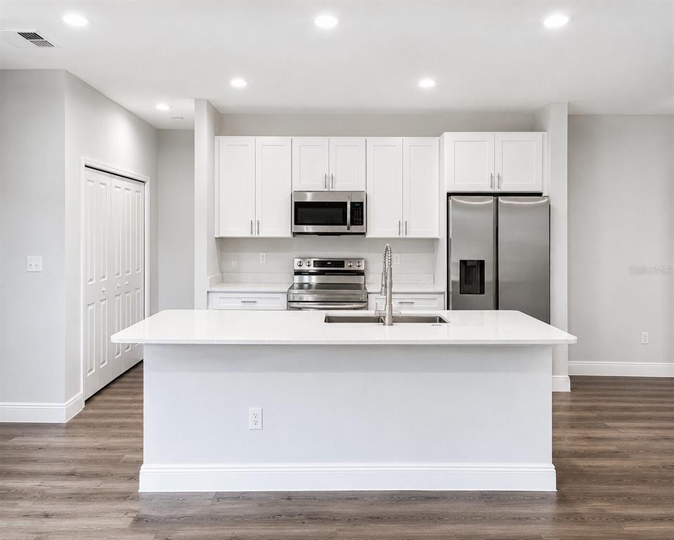 A modern kitchen features white cabinets, stainless steel appliances, and a large central island — 39 WATER TRACK DRIVE, OCALA, FL