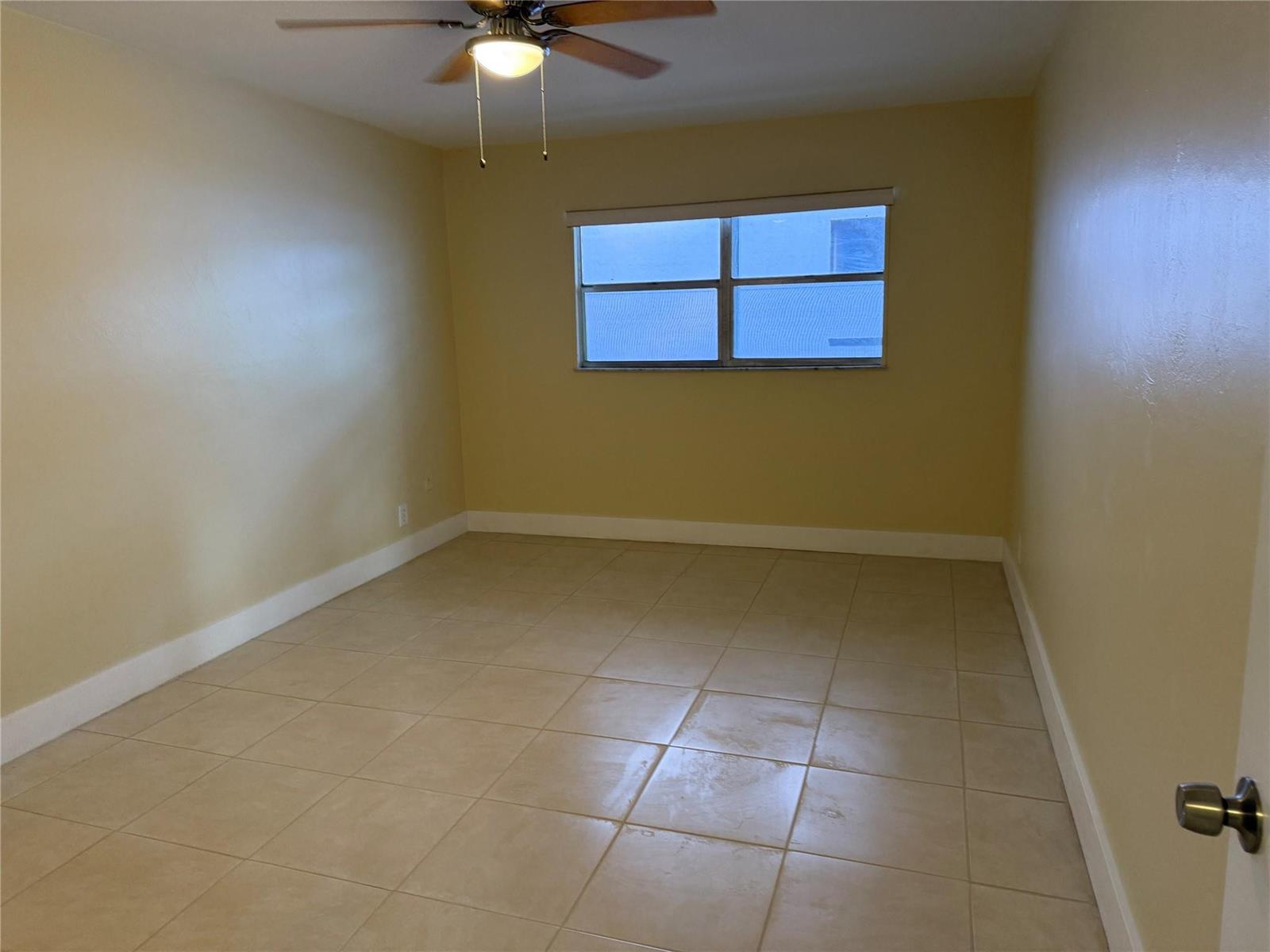 An empty bedroom features beige walls, light-colored tile flooring, and a ceiling fan — 1450 N Riverside Drive # 204, Pompano Beach FL 33062, POMPANO BEACH, FL
