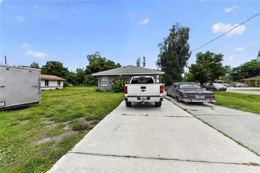 A gray house with a concrete driveway, a white pickup truck, and a black sedan — 1904 2ND AVENUE E, PALMETTO, FL