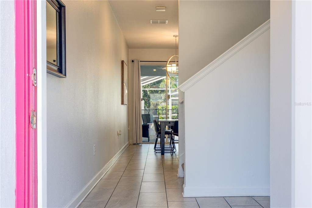 A tiled hallway leads past a staircase toward a dining area with a sliding glass door — 650 PEBBLE BEACH DRIVE, DAVENPORT, FL