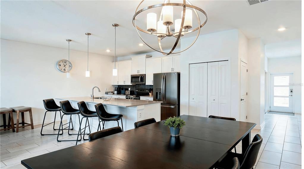 A kitchen and dining area features a large island, stainless steel appliances, and tile flooring — 650 PEBBLE BEACH DRIVE, DAVENPORT, FL