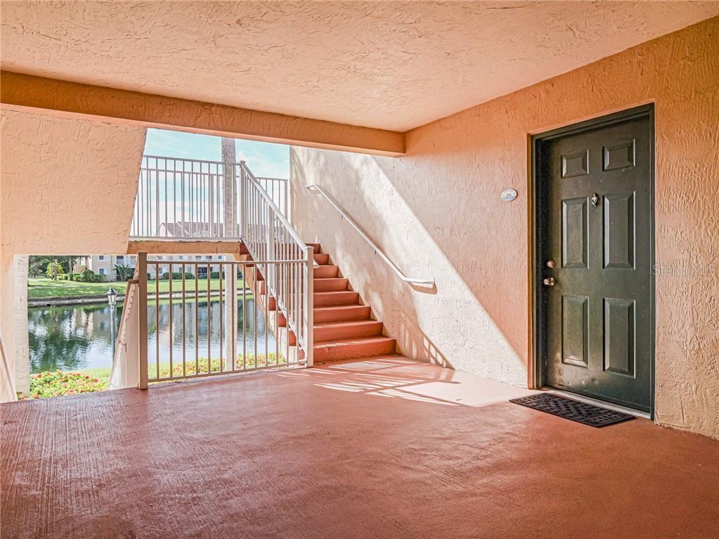 An outdoor covered entryway features a dark door, concrete flooring, and stairs leading upward — 1640 N 42ND CIRCLE UNIT 206, VERO BEACH, FL